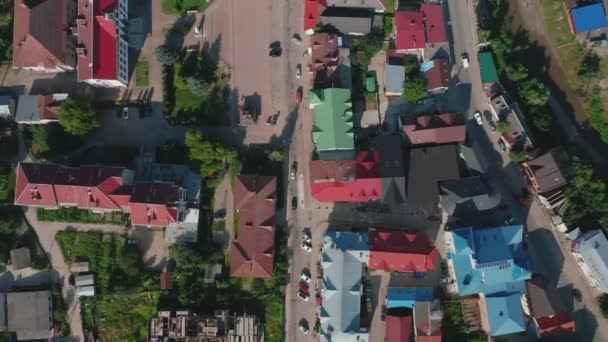 Vista aérea de los tejados de las casas de una pequeña ciudad con un río, puente y coches. — Vídeo de stock