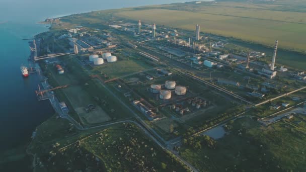 Vista aérea de uma instalação química localizada entre o porto e os campos agrícolas ao pôr-do-sol. — Vídeo de Stock