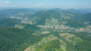 Aerial drone view of a township in a mountain valley against a blue sky.