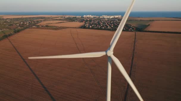 Luchtfoto van een windmolen tegen de township en landbouwgrond op een mooie zomeravond. — Stockvideo