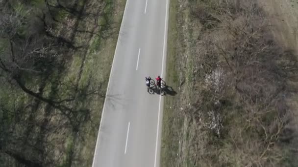 Veduta aerea di una giovane coppia di ciclisti che cavalcano verso un'auto della polizia. — Video Stock