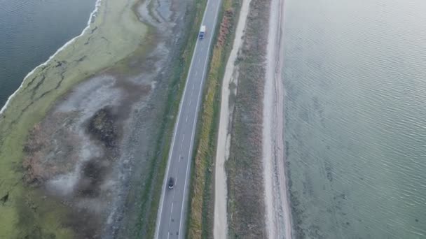 Vista aérea de los coches que circulan por una carretera entre grandes lagos. — Vídeo de stock