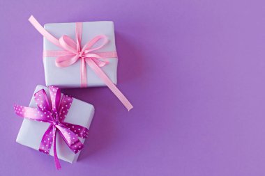 Pembe ve mor benekli iki hediye kutusu mor arka planda benekli kurdele.