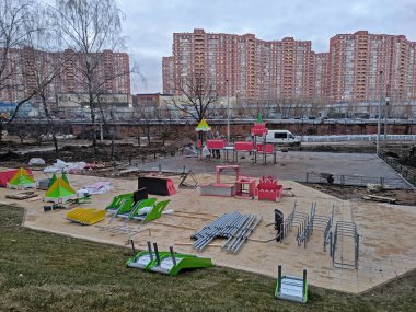 Parkın metal parçaları kaldırım taşlarının üzerinde şehir parkındaki oyun parkının yanında duruyor.