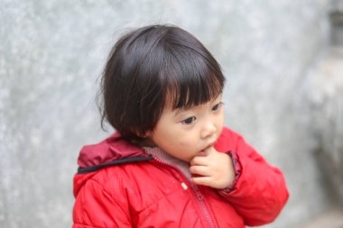 Vietnamlı genç ve şirin bir çocuğun parmağını emmesi.