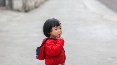 Vietnamlı küçük kız yolda sessiz bir jest yaptığı için parmaklarını dudaklarına kadar uzattı.
