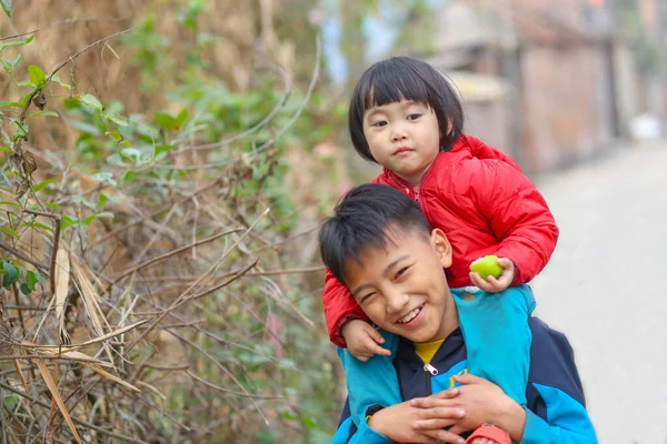Szczęśliwy Uśmiechnięty Wietnamczyk Trzymający Swoją Młodszą Siostrę Szyi Drodze Obraz Stockowy