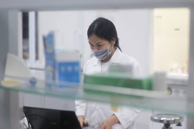 Vietnamlı kadın bilim adamı laboratuvarda dizüstü bilgisayarla çalışıyor.