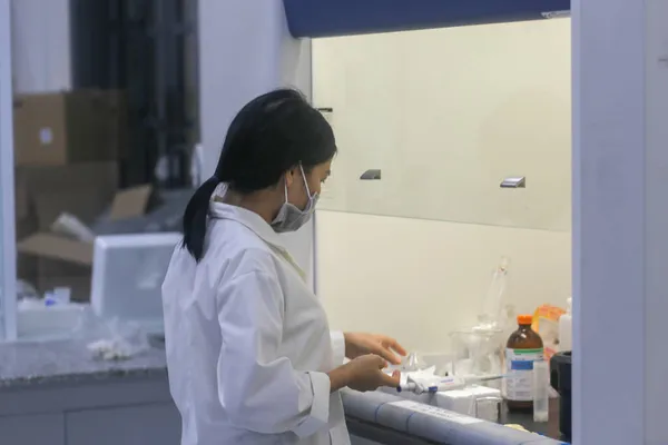 Asyalı kadın bilim adamı laboratuarda ekipman hazırlıyor.