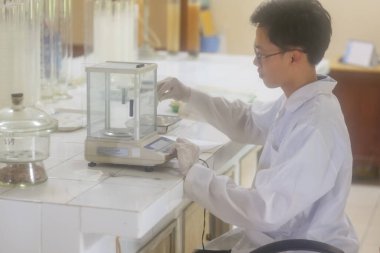 Vietnamlı bilim adamı laboratuvarda dijital laboratuvar ölçeği kullanıyor.