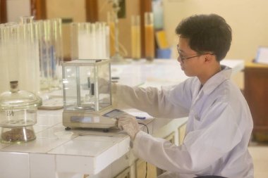 Vietnamlı bilim adamı laboratuvarda dijital laboratuvar ölçeği kullanıyor.