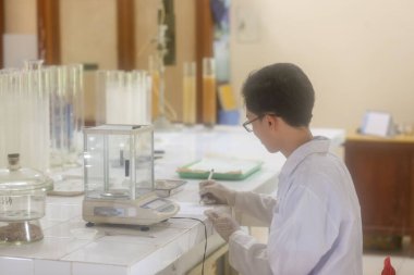 Vietnamlı bilim adamı laboratuvarda dijital laboratuvar ölçeği kullanıyor.