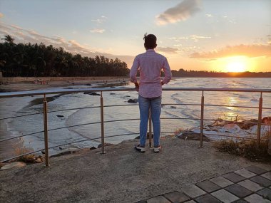 Bir adam durur ve gün batımını seyreder