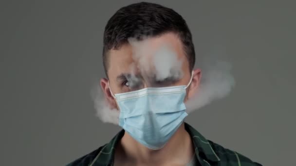 Ung kaukasisk man som andas ut ånga från ånga genom medicinsk mask Stockfilm