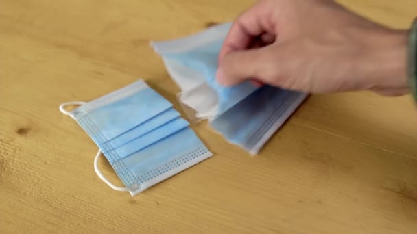 Man neemt nieuwe medische masker doormidden gesneden en toont zijn verschillende lagen — Stockvideo