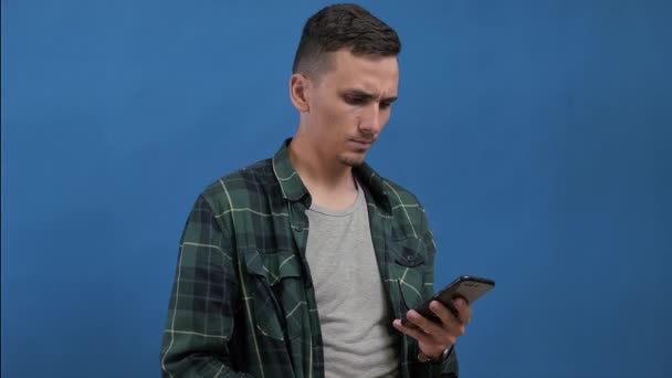 Muž sedí s telefonem, pak si otře obrazovku lékařskou maskou a zahodí ji — Stock video