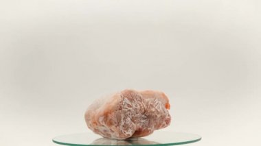 Pieces of frozen rotating meat on a white background, from which blows frosty freshness and cold. Close-up. Place for your text
