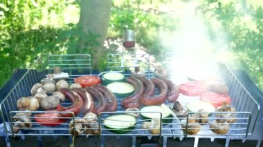 Fried sausages and vegetable on the grill outdoors. B-B-Q. Fried food is fried and smoked on charcoal grills. It turns out a grill with delicious tasty sausages, vegetables, champignon mushrooms.