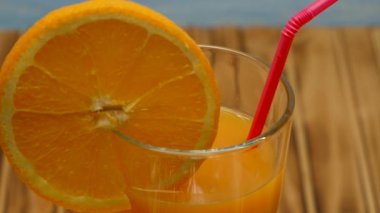 Rotation of orange juice in a glass. Cocktail with orange juice on a wooden background. Close up.