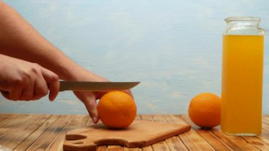 Man's hands cuts orange on cutting wooden board of home in kitchen. Orange citrus fruits, making fresh juice or tropical cocktails. Healthy food concept. 4k.