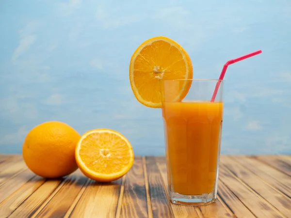 Orange juice in a glass with a slice of orange and an straw.