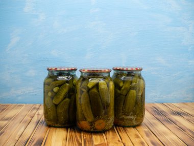 Preservations, conservation. Salted, pickled cucumbers in a jars on an wooden table. Pickling cucumbers at home. Vegetable harvest conservation. Close up.