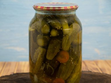 Preservations, conservation. Salted, pickled cucumbers in a jar on an wooden table. Pickling cucumbers at home. Vegetable harvest conservation. Close up.