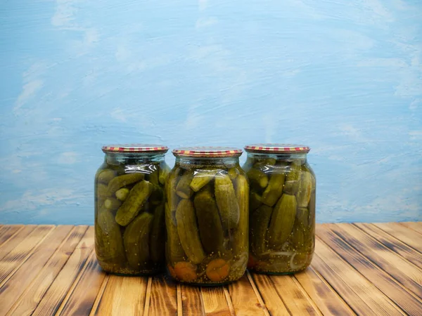 Preservations, conservation. Salted, pickled cucumbers in a jars on an wooden table. Pickling cucumbers at home. Vegetable harvest conservation. Close up.