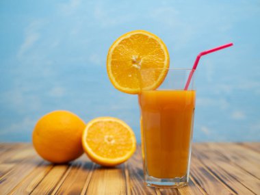 Ripe bio oranges and a glass of fresh squeezed orange juice on wooden background. Organic Sicilian oranges.