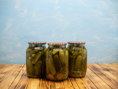 Preservations, conservation. Salted, pickled cucumbers in a jars on an wooden table. Pickling cucumbers at home. Vegetable harvest conservation. Close up.