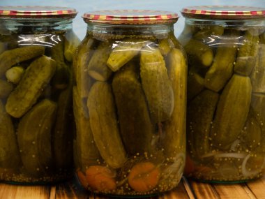 Preservations, conservation. Salted, pickled cucumbers in a jars on an wooden table. Pickling cucumbers at home. Vegetable harvest conservation. Close up.