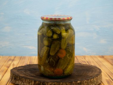 Preservations, conservation. Salted, pickled cucumbers in a jar on an wooden table. Pickling cucumbers at home. Vegetable harvest conservation. Close up.