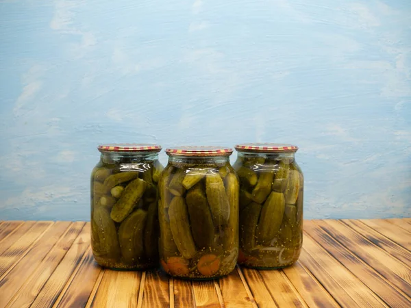 Preservations, conservation. Salted, pickled cucumbers in a jars on an wooden table. Pickling cucumbers at home. Vegetable harvest conservation. Close up.