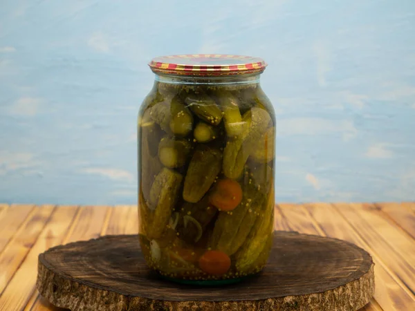 Preservations, conservation. Salted, pickled cucumbers in a jar on an wooden table. Pickling cucumbers at home. Vegetable harvest conservation. Close up.
