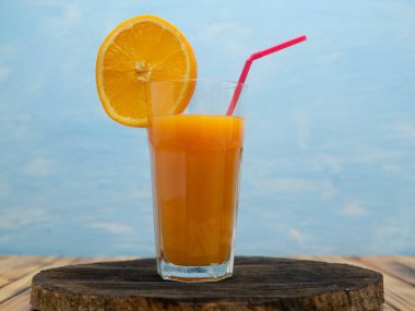 Fresh juice, mix fruits, orange drink on a blue background. Glass with orange cocktail.