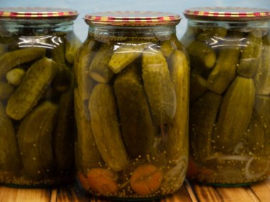Preservations, conservation. Salted, pickled cucumbers in a jars on an wooden table. Pickling cucumbers at home. Vegetable harvest conservation. Close up.