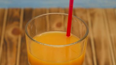 Rotation of orange juice in a glass. Cocktail with orange juice on a wooden background. Close up.