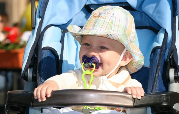 一岁的男婴 带着奶嘴 从婴儿车里望着 微笑着 — 图库照片