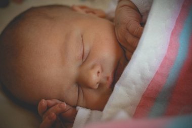 One day old newborn boy infant is sleeping under blanket clipart