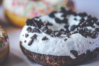 Siyah kurabiyelerle süslenmiş beyaz jöleli halka çöreğin yakın çekimi.