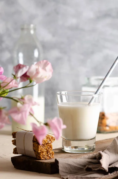 ガラスとミルクのボトル シリアルバー 瓶の中のアーモンドとピンクの花の茶色のナプキン — ストック写真