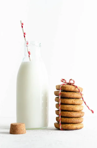 赤と白のわらとクッキーの山が積み上げられ 白い背景に赤と茶色の文字列で結ばれた牛乳のボトル — ストック写真