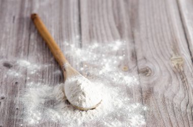 Tahta zemin üzerinde bir kaşık beyaz un. Boşluğu kopyala. 