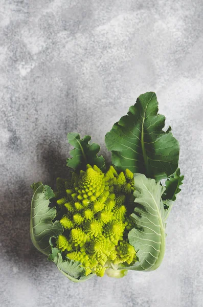 Romanesco broccoli with leaves on grey background with copy space. 