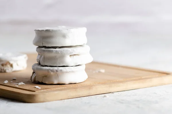 White alfajores filled with dulce de leche on a wooden board and white background. 