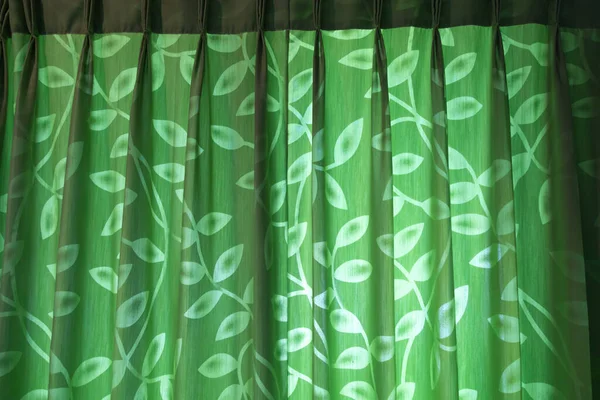 Green curtains with leaf motifs shine from outside the room with interesting shadows. For background.