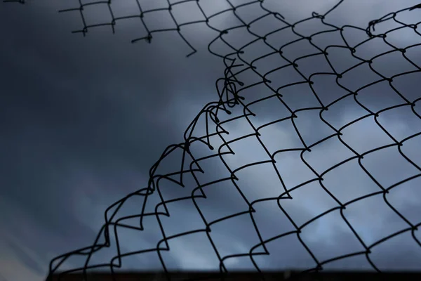 曇天に対する壊れた金属メッシュフェンス — ストック写真