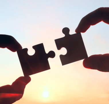 Gökyüzü arka planında yapboz parçaları olan eller.  