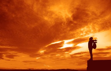 Sırt çantalı sırt çantalı sırt çantalı silueti vadinin yukarısındaki kayalık manzarada duruyor.. 