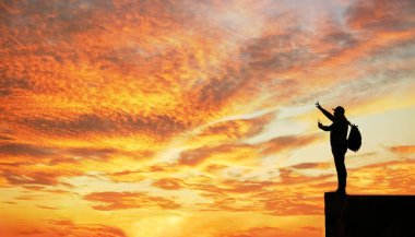 Gün batımında dağda duran turist silueti. İşaret parmağının yönünü gösterir